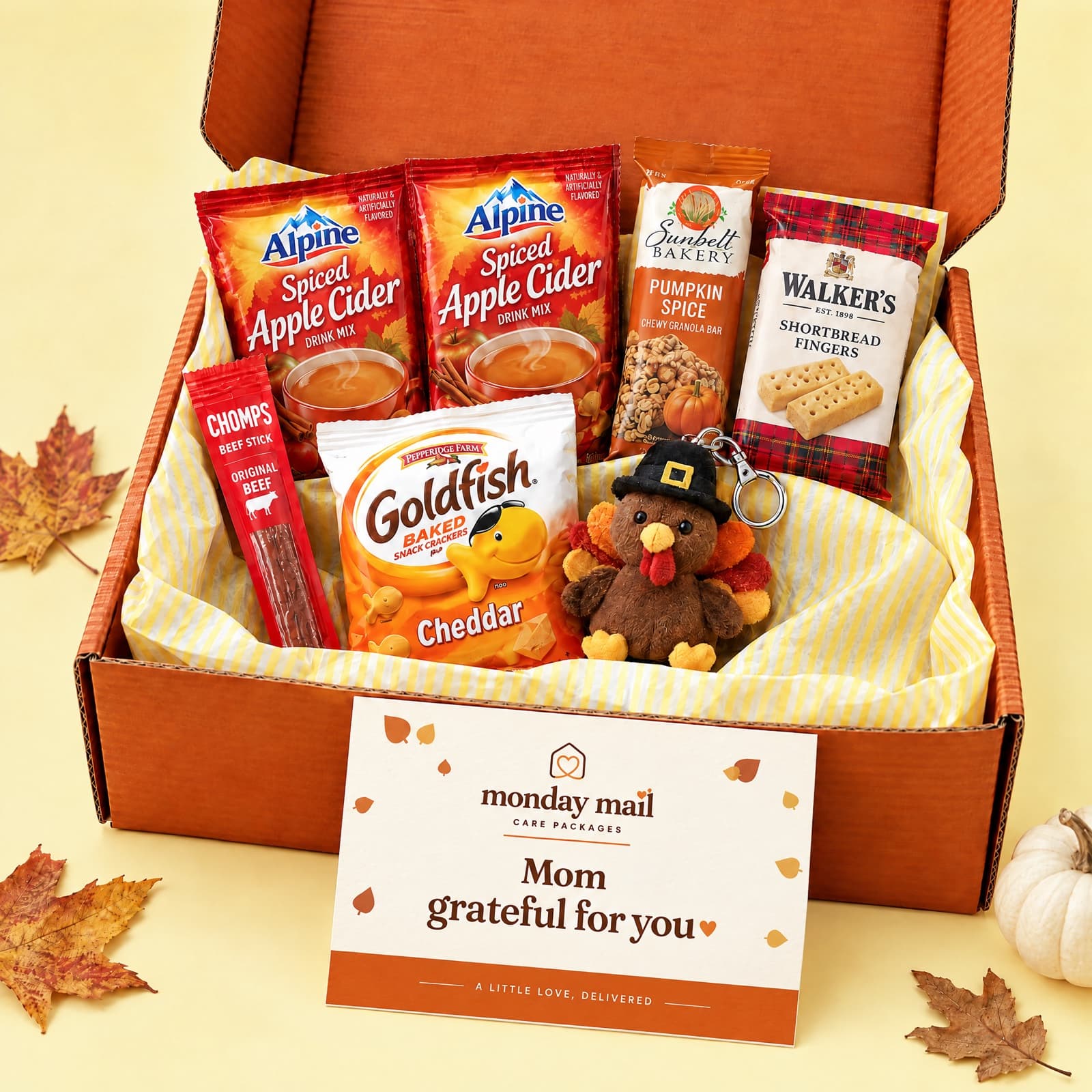The orange Grateful for You box with spiced apple cider, a pumpkin spice bar, shortbread and a plush turkey